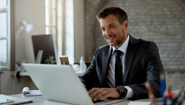 Happy businessman using laptop while working in the office.